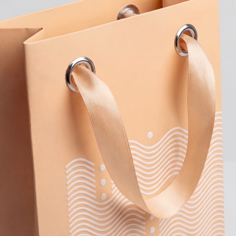 Бумажный пакет с люверсами и атласными ручками крупным планом