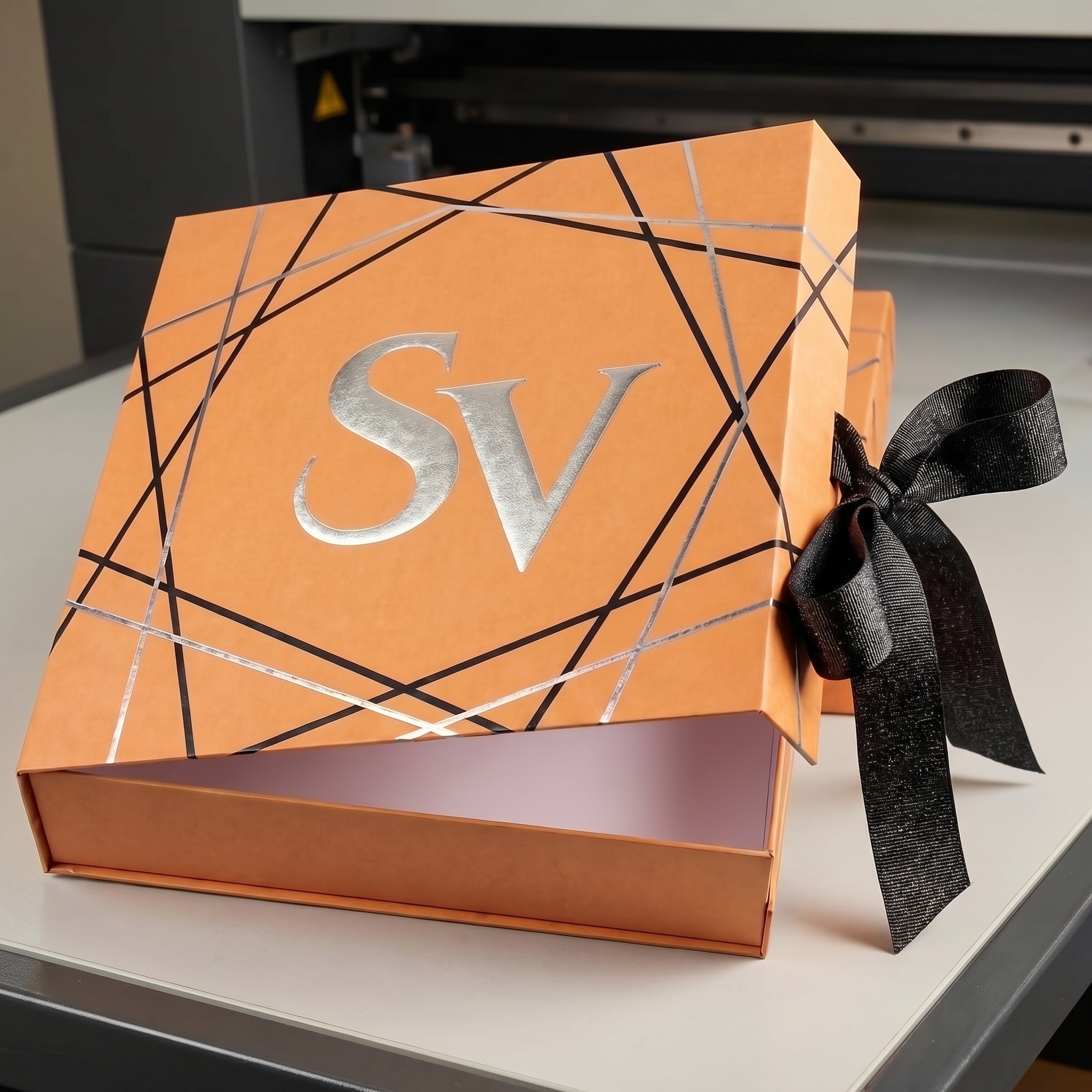 SV — оранжевая коробка с магнитом с серебряным тиснением и чёрной лентой