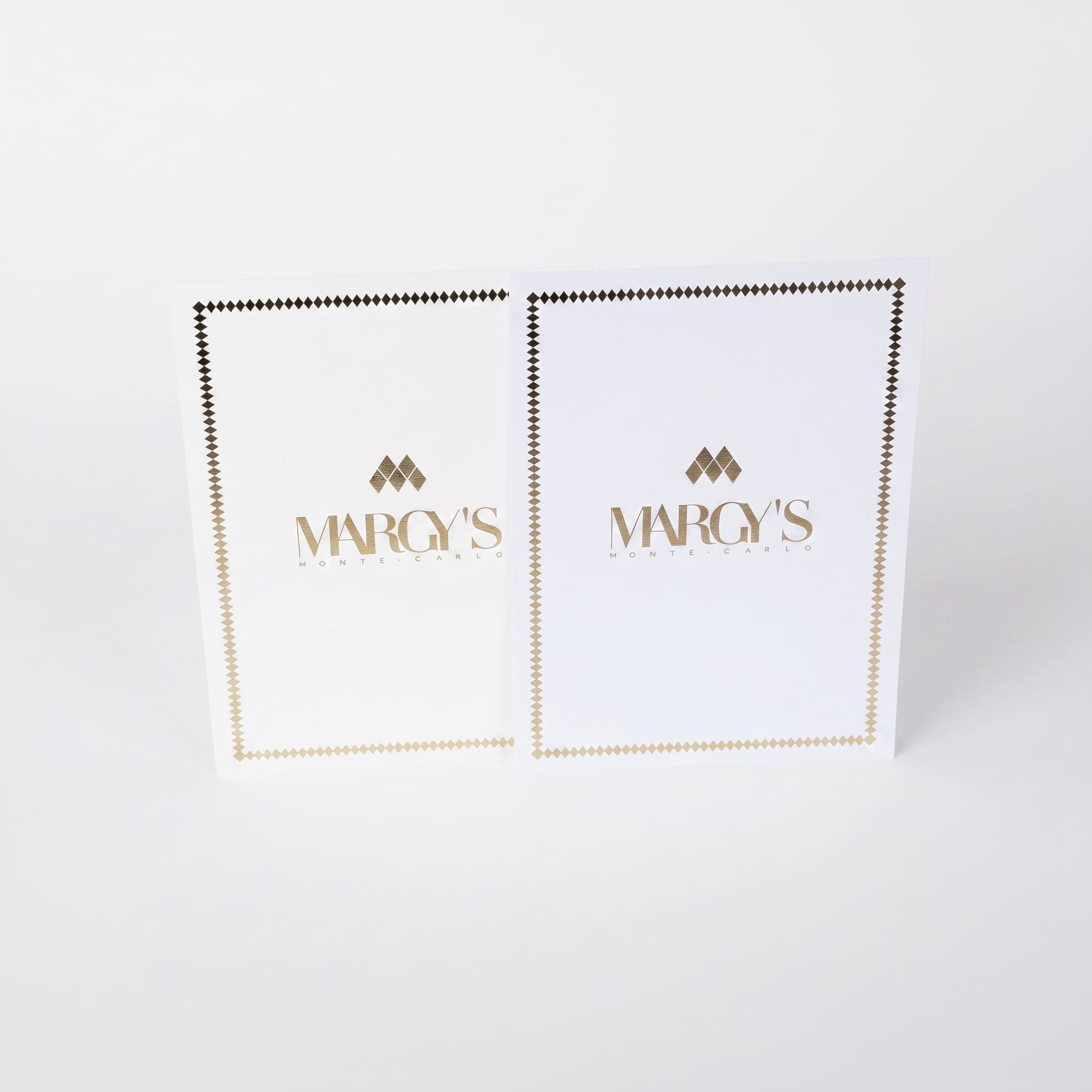 Margy's Monte Carlo — две белые листовки с золотым тиснением, вид сбоку